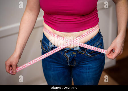 Grosse fille bande détient-mesure sur son ventre. Banque D'Images