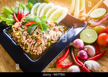 Salade de porc haché épicé Thai Food servi sur table avec des herbes et épices Ingrédients / nord-est de tradition Isaan des aliments sur la plaque avec de délicieux légumes frais Banque D'Images