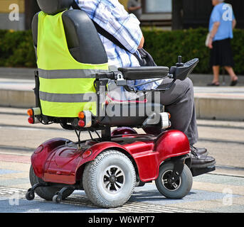 Vieil homme avec un fauteuil roulant dans la rue electirc Banque D'Images