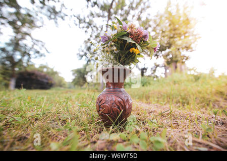 Bouquet de fleurs sauvages sauvages colorés dans un pot en argile posés sur l'herbe Banque D'Images