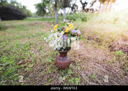 Bouquet de fleurs sauvages sauvages colorés dans un pot en argile posés sur l'herbe Banque D'Images