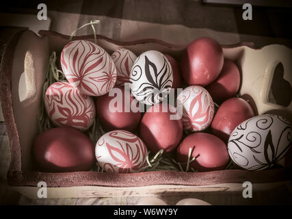 Une boîte pleine d'oeufs de Pâques avec des fleurs à la main Banque D'Images