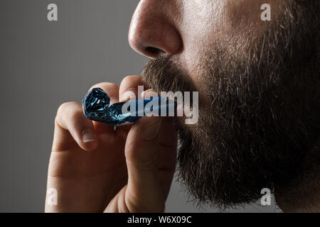 Homme à barbe d'une partie de la soufflerie de l'avertisseur sonore sur fond gris Banque D'Images