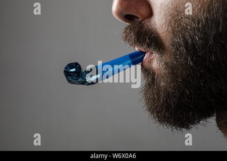 Homme à barbe d'une partie de la soufflerie de l'avertisseur sonore sur fond gris Banque D'Images