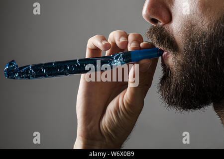 Homme à barbe d'une partie de la soufflerie de l'avertisseur sonore sur fond gris Banque D'Images