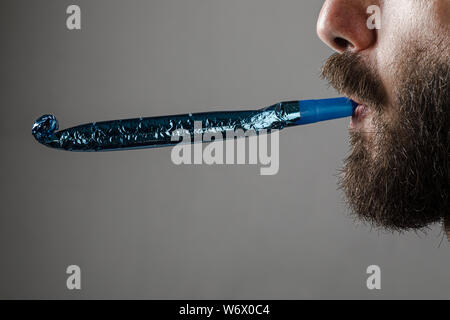 Homme à barbe d'une partie de la soufflerie de l'avertisseur sonore sur fond gris Banque D'Images