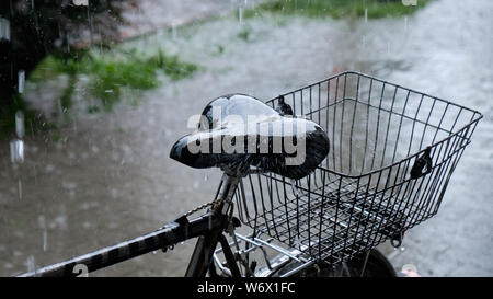 La forte pluie qui tombe sur une selle de vélo garé sur le trottoir. L'accent sur le siège, reste fortement brouillé Banque D'Images