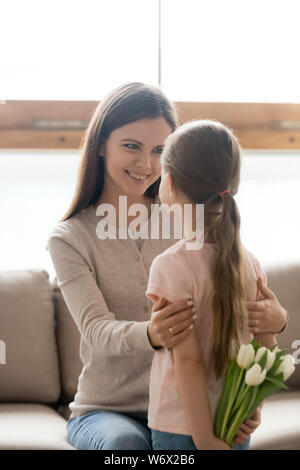 Adorable fille tenant des fleurs faire une surprise pour maman Banque D'Images