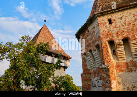 Alma Vii - l'église fortifiée rénové murs extérieurs dans le coucher du soleil chaud de la lumière. Destination touristique dans les régions rurales de la Transylvanie, Roumanie. Banque D'Images