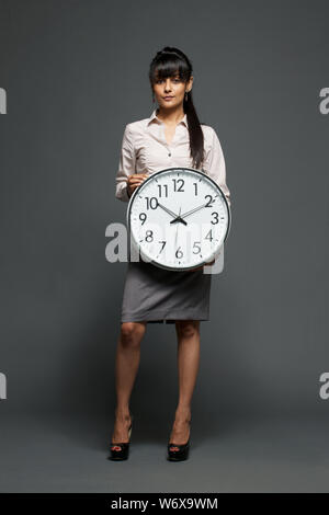 Businesswoman holding a clock Banque D'Images