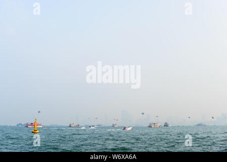 Sports de mer à Pattaya, Thaïlande. Divers bateaux et navires dans la mer en face de vue sur la ville à l'horizon. Banque D'Images