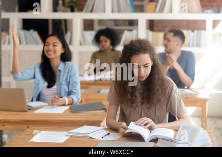 Les filles et les gars des étudiants assis en classe pendant l'exposé Banque D'Images