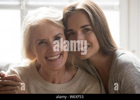 Mère d'âge moyen grandi fille embrassant looking at camera Banque D'Images