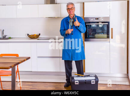 Homme mature est debout dans la cuisine près de la boîte à outils et à happy Banque D'Images