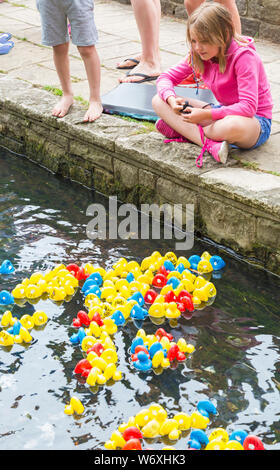 Bournemouth, Dorset, UK. 3e août 2019. 2000 canards jouet course à Bourne stream dans Jardins de Bournemouth au cours d'aujourd'hui et demain. Organisé par falaise Est Rotary Club au profit d'organismes de bienfaisance locaux l'événement est sûr d'être quackers ! La foule s'applaudir les canards dans l'espoir que la leur sera la gagnante. Fille est assise regardant le passé, les canards flottant flottant par. Credit : Carolyn Jenkins/Alamy Live News Banque D'Images