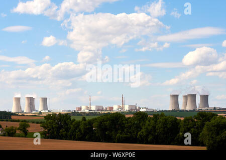 Vue sur les cheminées de fumer d'une centrale nucléaire dans le paysage avec des arbres, champs et maisons sous ciel bleu avec des nuages. Banque D'Images