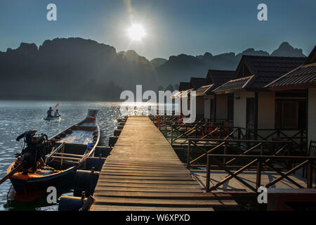 Longue queue bateaux flottant sur l'eau avec de beaux rayons de lumière sur la montagne à une cabane en bambou Saichon à Khao Sok, Surat Thani, Thaïlande. Banque D'Images