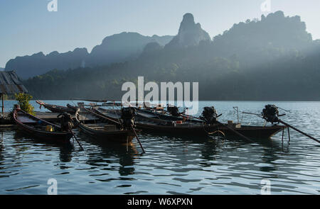 Longue queue bateaux flottant sur l'eau avec de beaux rayons de lumière sur la montagne à une cabane en bambou Saichon à Khao Sok, Surat Thani, Thaïlande. Banque D'Images