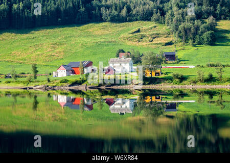 La ferme d'été traditionnel norvégien le long du lac Vangsvatnet reflète dans l'eau près du comté de Hordaland en Norvège Voss Banque D'Images