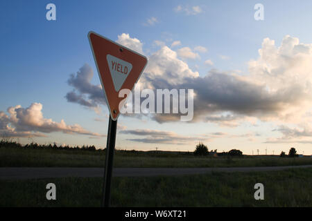 Landsacpe photo d'un rendement en regard d'un chemin rural avec un générateur de vent dans l'arrière-plan et nuages duveteux de nice Banque D'Images