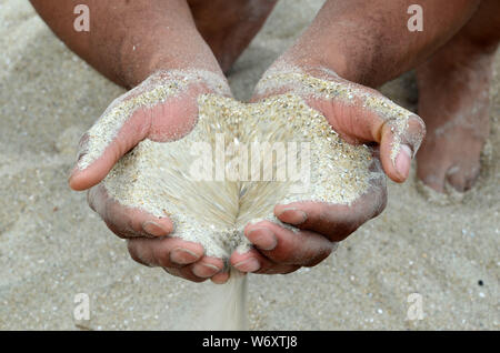 ADN humain : un homme et une femme qui squatter sur la plage de Tybee ont du sable qui coule à travers leurs mains. Banque D'Images