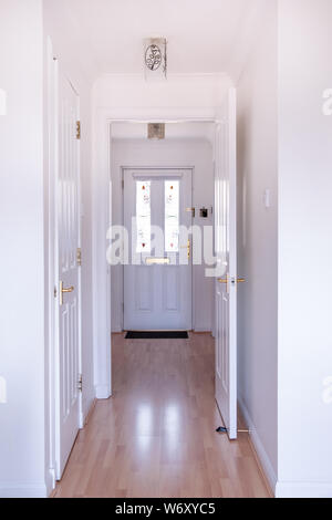 L'entrée moderne de chambre avec couloir des sols stratifiés et tout peint en blanc couleurs propres. A Porte inserts en verre teinté à ajouter à la m Banque D'Images