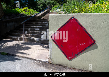 En forme de rendement panneau rouge sur barrière de béton au début de l'escalier qui mène au park Banque D'Images