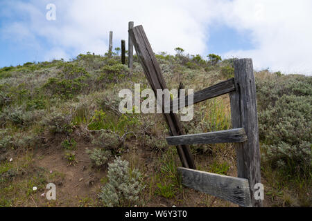 Clôture en bois rustique et brisé assis sur colline herbeuse en sentier pédestre Banque D'Images