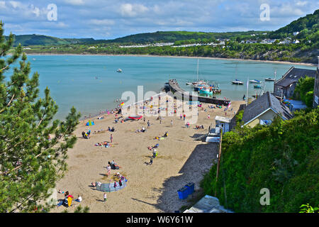 Une vue tranquille surplombant la jolie plage à Newquay avec bateaux de pêche amarrés dans l'abri de la digue. Les familles jouant sur une plage de sable. Banque D'Images