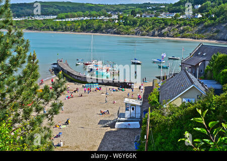 Une vue tranquille surplombant la jolie plage à Newquay avec bateaux de pêche amarrés dans l'abri de la digue. Les familles jouant sur une plage de sable. Banque D'Images