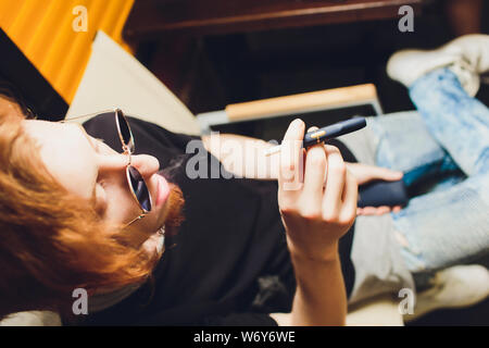 Fumeur de cigarettes sans fumée hybride qui utilise des recharges de tabac, une technologie hybride entre les cigarettes électroniques et analogiques. Banque D'Images