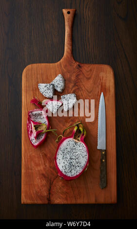 Coupe de fruits Dragon sur une planche à découper en bois avec un couteau sur une table en bois Banque D'Images