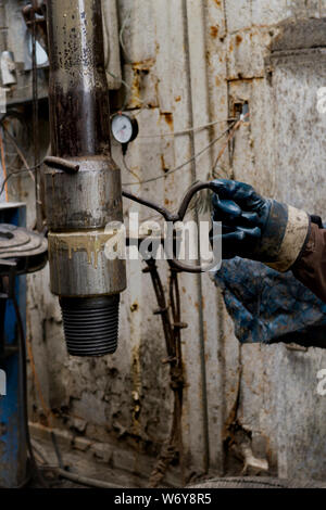 Derrick. Le sous-tire le foreur des tiges de forage à l'aide d'un crochet dans les gants de protection. La sécurité dans le forage de puits de pétrole et de gaz. Forage. Ind d'huile Banque D'Images