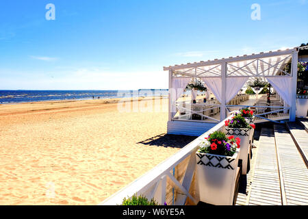 Restaurant d'été sur la plage avec des rideaux voletant dans le vent. Cireur des vagues de la mer. Blue sea surface de l'eau. Réflexion du soleil sur l'eau s Banque D'Images