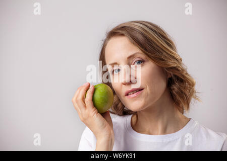 Smiling belle femme adulte avec une pomme sur fond gris Banque D'Images
