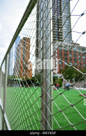 Terrain de soccer concept non mise au point dans la ville de New York., Manhattan, entre les gratte-ciel. Clôture en premier plan l'accent. Banque D'Images