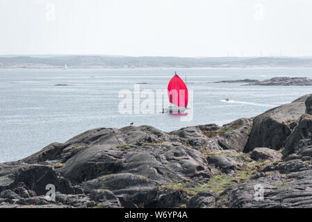 Ursholmen, Suède - Juillet 26, 2019 : Avis d'un voilier avec un voile rouge à l'extérieur de l'île de Ursholmen dans le Parc National de Kosterhavet suédois dans l'ouest Banque D'Images
