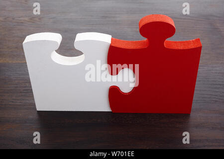 Deux détails de blanc et rouge sur fond de bois foncé de puzzle. Banque D'Images