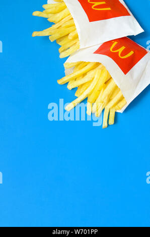 KHARKIV, UKRAINE - 1 août 2019 : McDonald's les frites dans de petits the paperbag sur fond bleu lumineux. McDonald's Corporation est la plus grande organisation mondiale de Banque D'Images