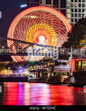 03 août 2019, Hessen, Frankfurt/Main : une grande roue tourne sur les rives de la main, tandis que les lumières de la presse se reflètent dans la rivière en face de l'excursion les navires (photo avec une longue exposition). Selon la ville, la folk festival, qui a été célébrée pour la première fois en 1340 pour consacrer l'Église Dreikönigskirche (à proximité des Trois Rois), était à l'origine considérée comme une ligne de vie par les marins et les pêcheurs à la rivière principale. Il aura lieu du 2 août au 5 août 2019. Photo : Frank Rumpenhorst/dpa Banque D'Images