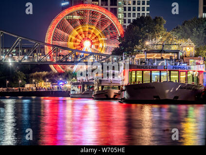 03 août 2019, Hessen, Frankfurt/Main : une grande roue tourne sur les rives de la main, tandis que les lumières de la presse se reflètent dans la rivière en face de l'excursion les navires (photo avec une longue exposition). Selon la ville, la folk festival, qui a été célébrée pour la première fois en 1340 pour consacrer l'Église Dreikönigskirche (à proximité des Trois Rois), était à l'origine considérée comme une ligne de vie par les marins et les pêcheurs à la rivière principale. Il aura lieu du 2 août au 5 août 2019. Photo : Frank Rumpenhorst/dpa Banque D'Images