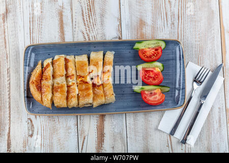 Tranches de burek avec fromage sur la planche de bois. Nourriture rustique. Nom : Kol Boregi turc. Banque D'Images