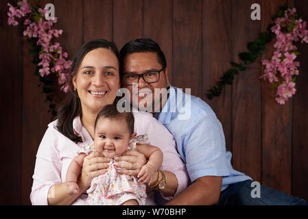 Happy Family Avec petit bébé fille sur fond de studio en bois Banque D'Images