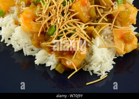 Close up of nude épicé crevettes aigre-doux sur le riz avec les nouilles de riz croustillantes sur plaque bleue Banque D'Images