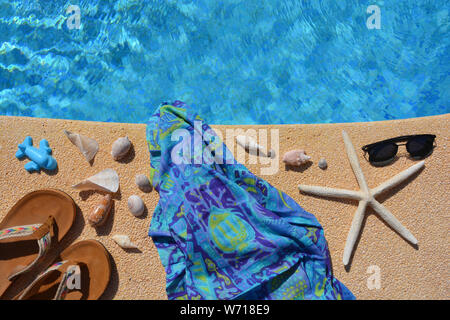 Appartement de vacances d'été. Des sandales, des étoiles de mer, coquillages, lunettes de soleil et des jouets de plage à côté d'une piscine. High angle view with copy space. Banque D'Images