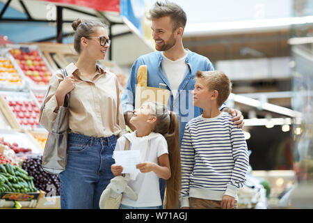 Portrait de famille contemporaine avec deux enfants shopping au marché de fermiers, copy space Banque D'Images