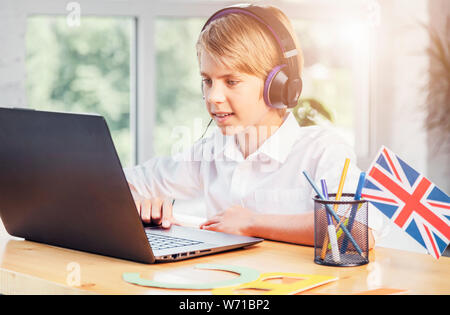 Les jeunes anglais en ligne stydying écolier using laptop Banque D'Images