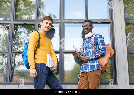 Portrait de deux étudiants holding books posant à l'extérieur dans les campus et à la caméra, à l'espace de copie Banque D'Images