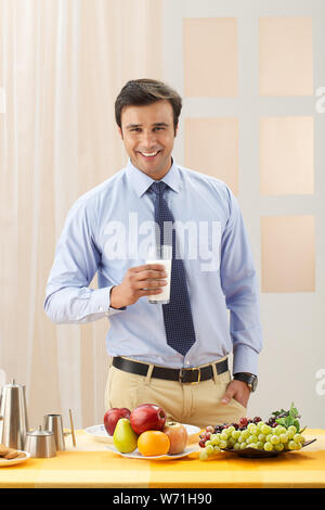 Businessman holding a glass of milk and smiling Banque D'Images