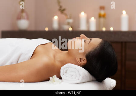 Vue de côté portrait de beau métis woman relaxing in spa de luxe prêt pour massage, copy space Banque D'Images